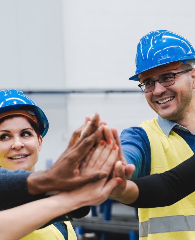 Happy multiracial engineer stacking hands while working at robotics warehouse